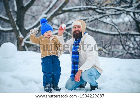 Father and son play with snowball on winter white background. Winter scene on white snow background. Father and son Having Fun in Winter Park