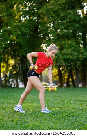 A young woman goes in for sports outdoors. girl with blond hair is training in the park on the nature.