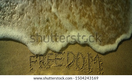 Concept or conceptual freedom text handwritten in sand on a beach with feet in an exotic island.free word written on the sand. Top view of human feet on summer beach