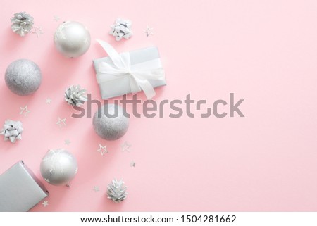 Silver Christmas decorations, balls, gift box, pine cones on pastel pink background. Xmas minimal composition with modern luxury decor. Flat lay, top view, copy space