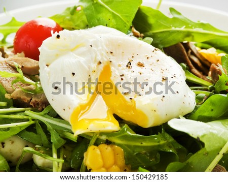 Pashot egg and salad with backed duck, rucola, cherry tomatoes, mozzarella and corn. Shallow dof.