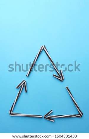 Recycling sign made of plastic straws on blue background. Plastic garbage, zero waste, recycle concept