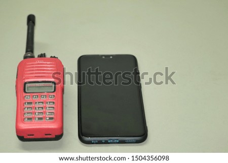 Two forms of communication Black smartphone with red portable radio transceivers on the table and works well in today's world.
