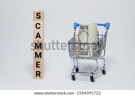 A picture of scammer word block with cart and fake money.  Scammer is unstoppable crime in the world.