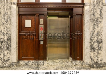 Old elevator with metal doors and wood grain paneling