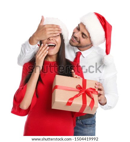 Young man presenting gift to his girlfriend on white background. Christmas celebration