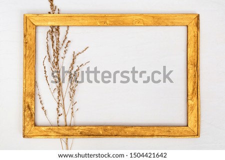 Blank gold frameÂ from wood with dry plant painted gold colored. Autumn creative still life. Minimal style background with copy space. 