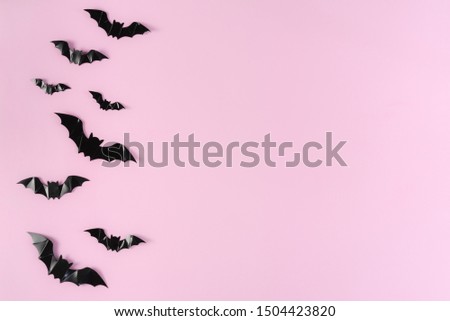 Black paper bats flying over pink background. Halloween and decoration concept.