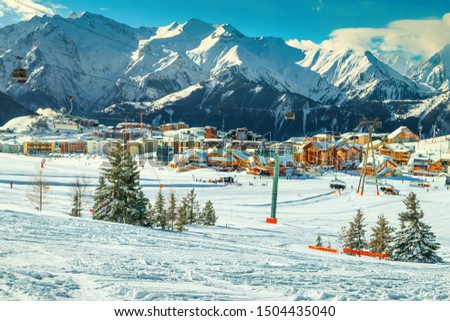 Popular alpine winter ski resort in French Alps. Picturesque cityscape with cable cars and ski slopes in the mountains, Alpe d Huez, France, Europe Royalty-Free Stock Photo #1504435040