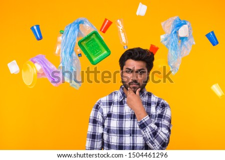 Problem of trash, plastic recycling, pollution and environmental concept - Serious Indian man looking forward on yellow background. He is thinking about ecology