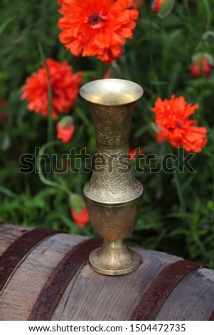 Oriental vase on a barrel of poppies. Bronze and ornament.