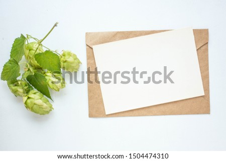 Minimalistic card mockup with 
hop branch, flower, craft envelope, blossom, flat lay, top view