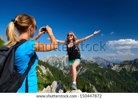 Young ladies with backpacks taking a pictures with Alps on the background