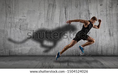Strong athletic man sprinter, running on dark wall background wearing in sportswear. Sport and fitness motivation Royalty-Free Stock Photo #1504524026