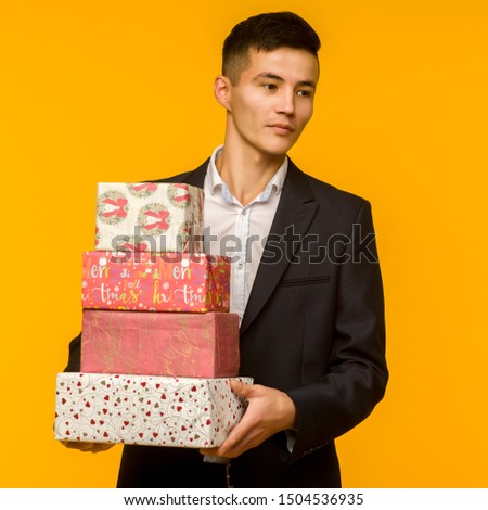 Handsome asian businessman holding christmas gift box over yellow background - image