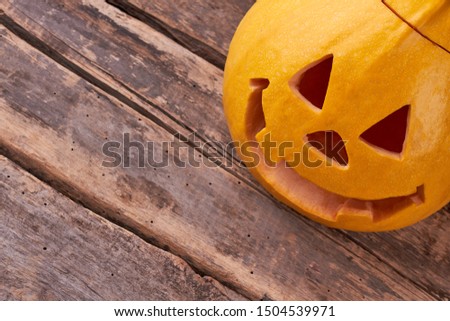 Carved pumpkin for Halloween. Traditional Halloween pumpkin on rustic wood. Halloween symbols and traditions.