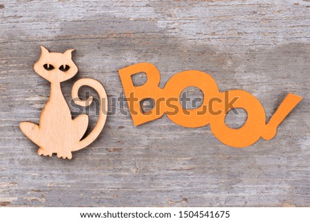 Halloween holiday decorations on wooden background. Wooden silhouette of cat and word boo on wooden surface.