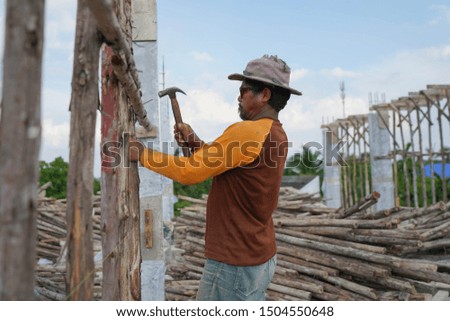 Construction worker hammering nail into wooden scaffolding at construction site.