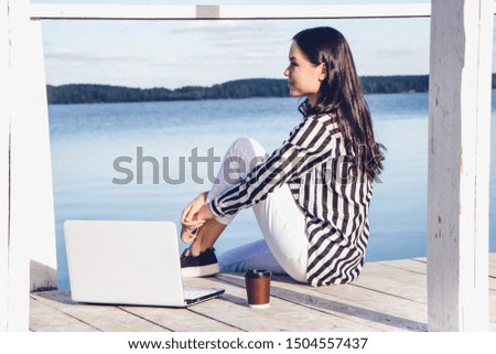 Girl on the lake with laptop and coffee