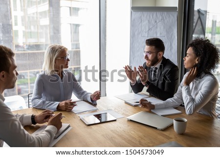 Serious multi-ethnic business entities gathered together for negotiating meeting lead by Arabian and aged businesspeople talk express opinion offer solutions solve current issues, partnership concept Royalty-Free Stock Photo #1504573049