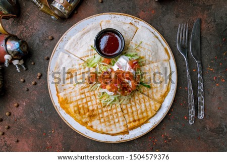Quesadilla with chicken and sauces on dark concrete rustic table