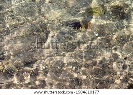 Detailed close up view on water surfaces with wave and ripples and the sunlight reflecting at the surface