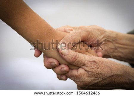 Hands of an elderly man hold the hands of a child. The concept of care and help for old people, the connection of the older and younger generation of people. Image. Royalty-Free Stock Photo #1504612466