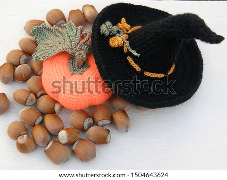 knitted witch hat with orange pumpkin and nuts on a white background.