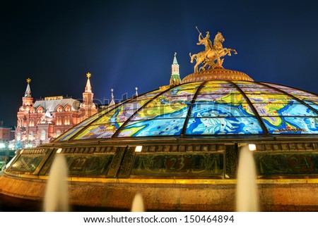 Statue of Saint George, patron of Moscow, on Manege Square at night, Moscow, Russia. Beautiful modern fountain with dome and map image, nice buildings in Moscow city center. Moscow landmarks theme.