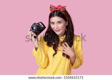 Portrait of a beautiful asian young woman taking picture by digital camera on pink background.