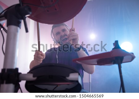 Music, drums, hobby and interests concept - Emotional drummer plays the drums. Photo with lighting motion effect
