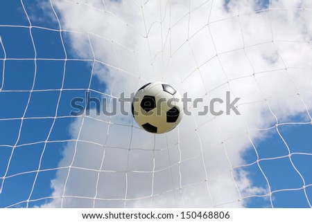 Soccer ball in net on blue sky background