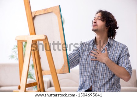 Young handsome man enjoying painting at home
