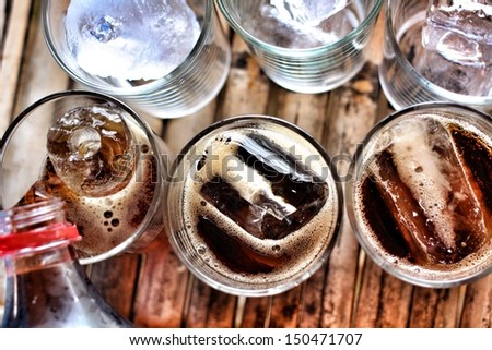 Pouring a glass of cola with ice cubes Royalty-Free Stock Photo #150471707