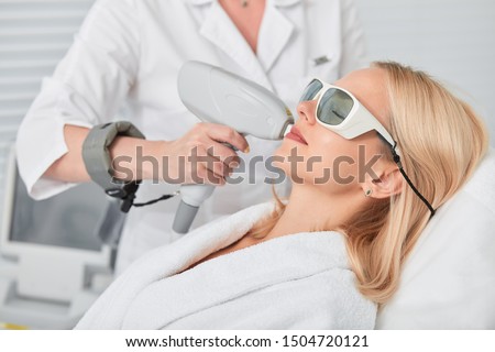 relaxed young blonde client receiving hair removal laser epilation. close up side view photo Royalty-Free Stock Photo #1504720121