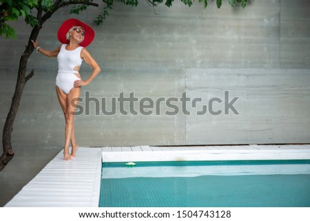 Senior lady in swimsuit touching tree and smiling stock photo. Website banner