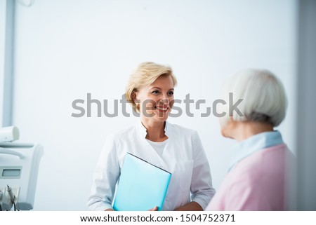 Happy doctor with her mature patient in clinic stock photo