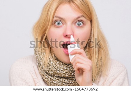 Treating her symptoms. Sick woman spraying medication into nose. Cute woman nursing nasal cold or allergy. Unhealthy girl with runny nose using nasal spray. Treating common cold or allergic rhinitis.