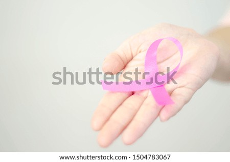 Pink ribbon in a woman's hand.Do not focus on objects.World Breast Cancer Day Concept.