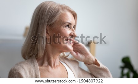Close up profile portrait smiling mature woman dreaming, thinking about good future, beautiful retired older female with healthy toothy smile looking in distance, feeling satisfied, natural beauty
