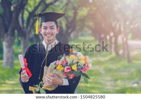 Happy graduate. Happy Asian man in graduation  holding diploma with bouquet of flowers Royalty-Free Stock Photo #1504825580