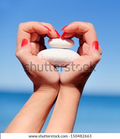 Female hand making a heart shape against a beautiful blue sky