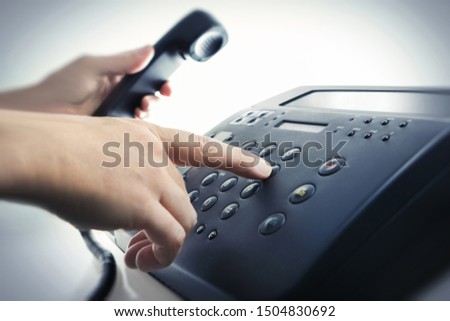 Male hand dialing with phone receiver 