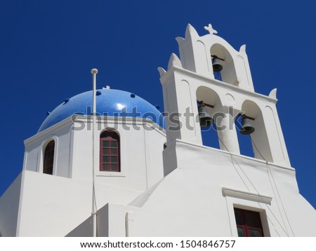The beautiful blue domes on the whitewashed cubiform architecture in  the Greek Village of Oia, on the Island of Santorini in the Aegean Sea are pictured along side lovely bell structures. Royalty-Free Stock Photo #1504846757