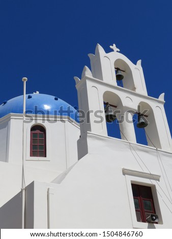 The beautiful blue domes on the whitewashed cubiform architecture in  the Greek Village of Oia, on the Island of Santorini in the Aegean Sea are pictured along side lovely bell structures. Royalty-Free Stock Photo #1504846760