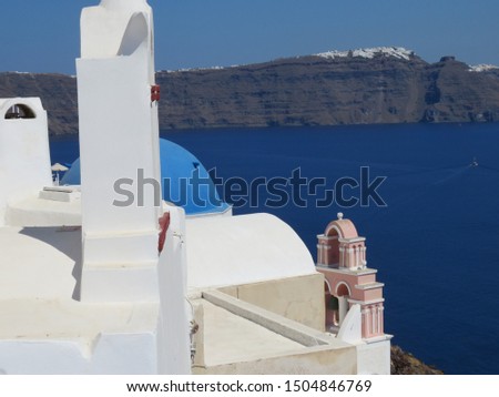 The beautiful blue domes on the whitewashed cubiform architecture in  the Greek Village of Oia, on the Island of Santorini in the Aegean Sea are pictured along side lovely bell structures. Royalty-Free Stock Photo #1504846769