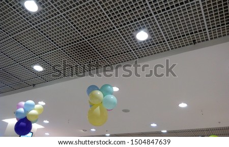 Perforated Grid ceiling and White Painted gypsum ceiling joints for an Retail shop during festival sale and decorated by hanging balloons