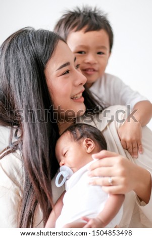Beautiful Asian mother have fun with her little boy and newborn baby in front of day light.