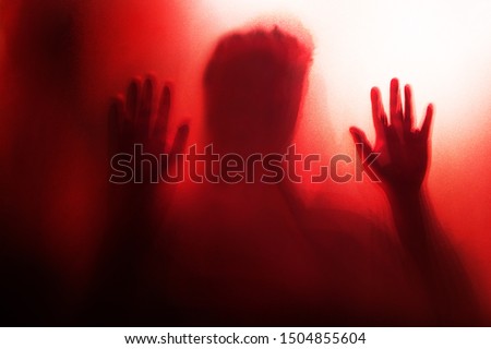 Shadow of the ghost hand behind frosted glass for horror concept