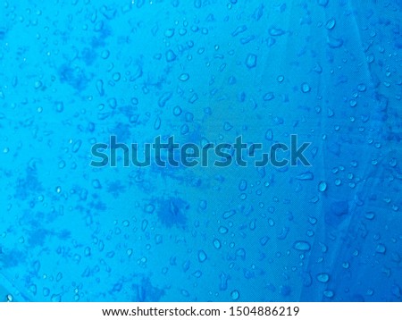 Rainwater on a blue umbrella pattern background.
